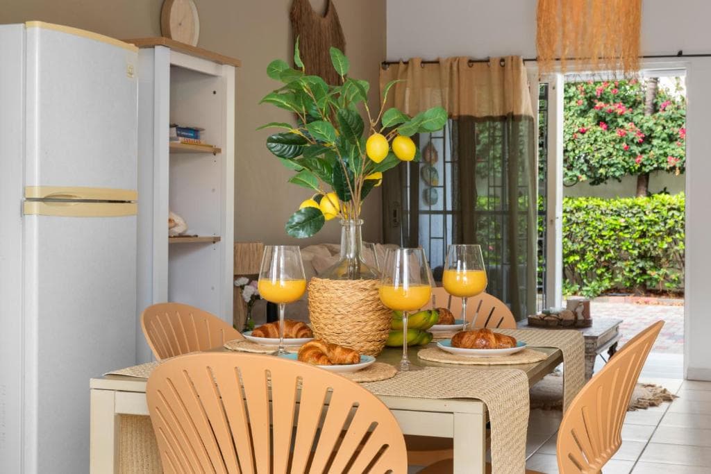 Gedekte eettafel met fruit en jus d'orange, koelkast en openslaande deuren naar buiten