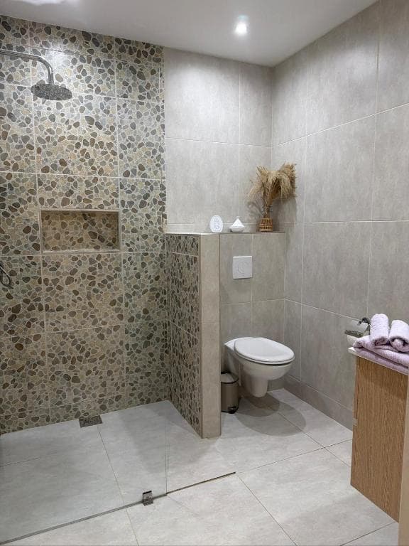 Badkamer met inloopdouche van kiezelsteen-tegels en hangend toilet