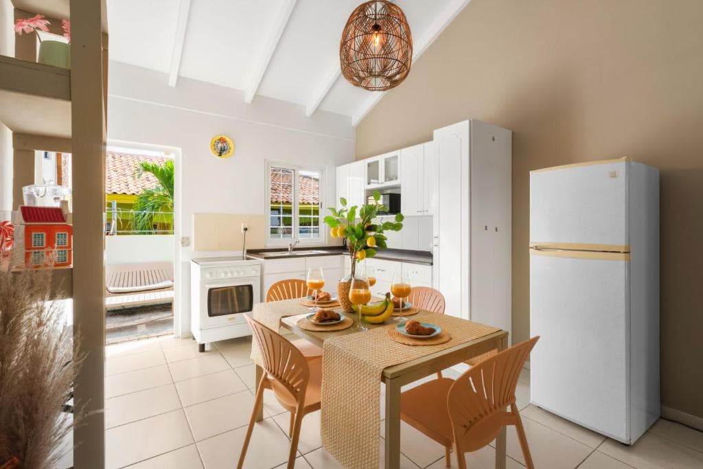 Open keuken met witte kastjes, fornuis en eettafel ervoor