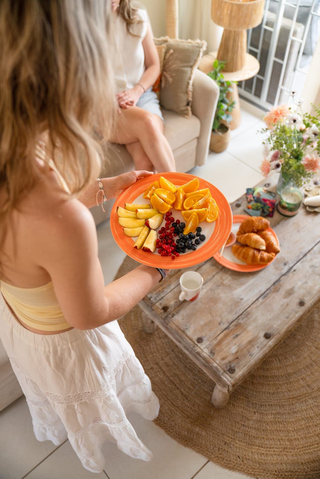 Bord met sinaasappel, appel, bessen en croissants op de houten salontafel