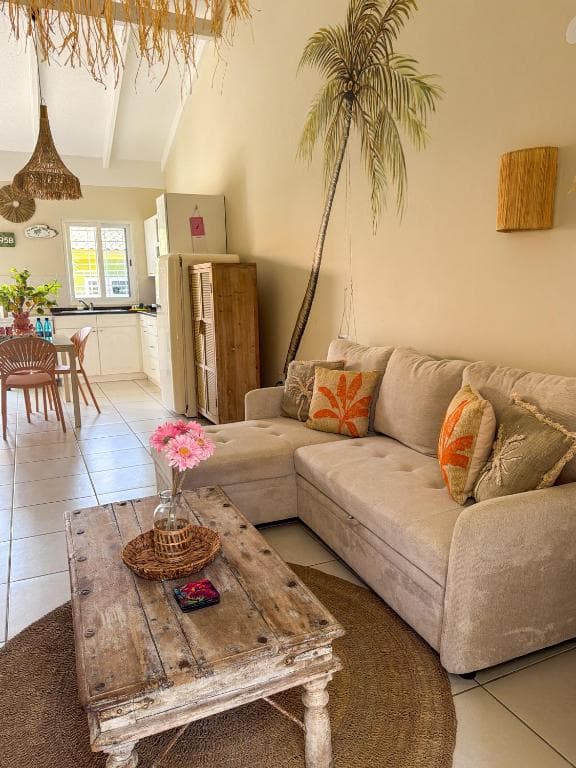 Woonkamer met beige hoekbank en palmboom-muurschildering